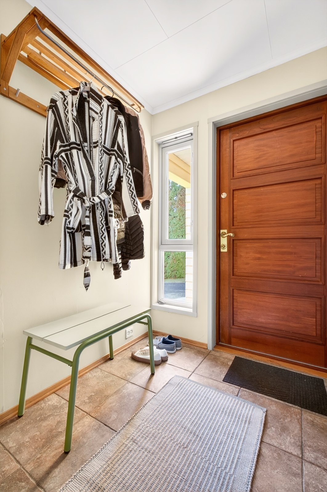 Innbydende entré med god plass til henging av yttertøy, fliser på gulv. Nymalt vegg i 2026. Sikringsskap og uttak til sentralstøvsuger er plassert i entréen. Galleribilde