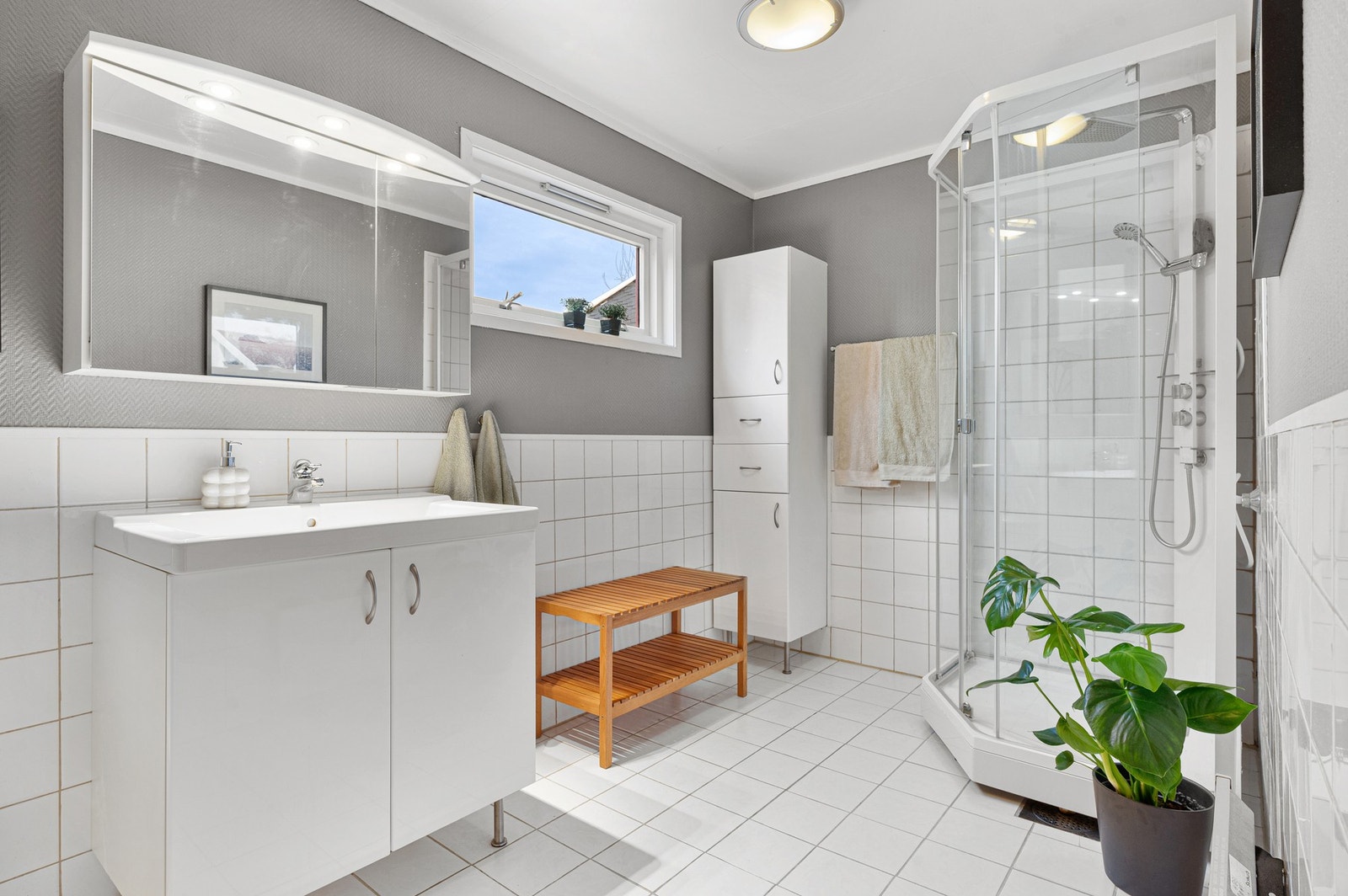 Lys og romslig bad - med dusjkabinett, vask med oppbevaringsplass og speilskap. Galleribilde