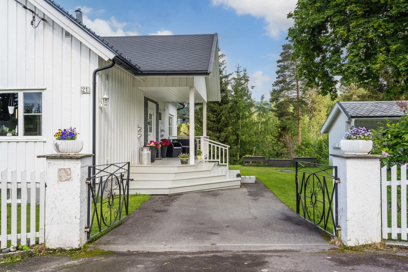 Velkommen inn til denne flotte eiendommen via smijernsporter og hvitt stakittgjerde Galleribilde