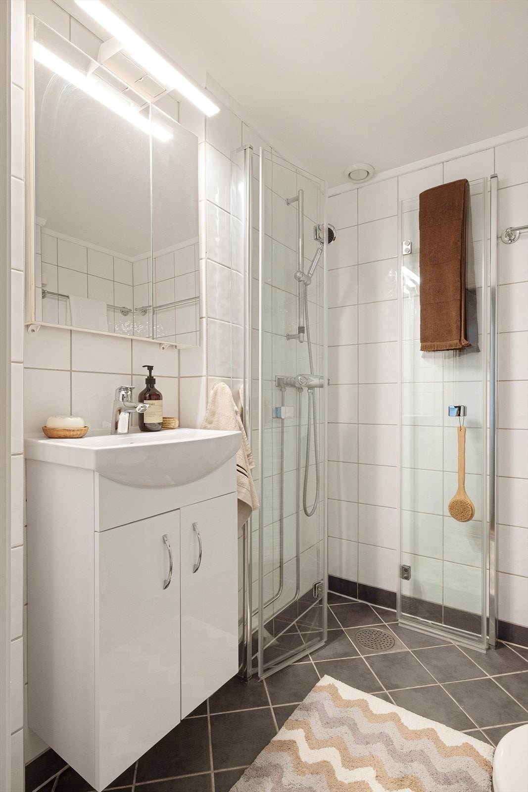 Rommet er innredet med servant med underskap, toalett og dusjhjørne med innfellbare dusjdører Galleribilde