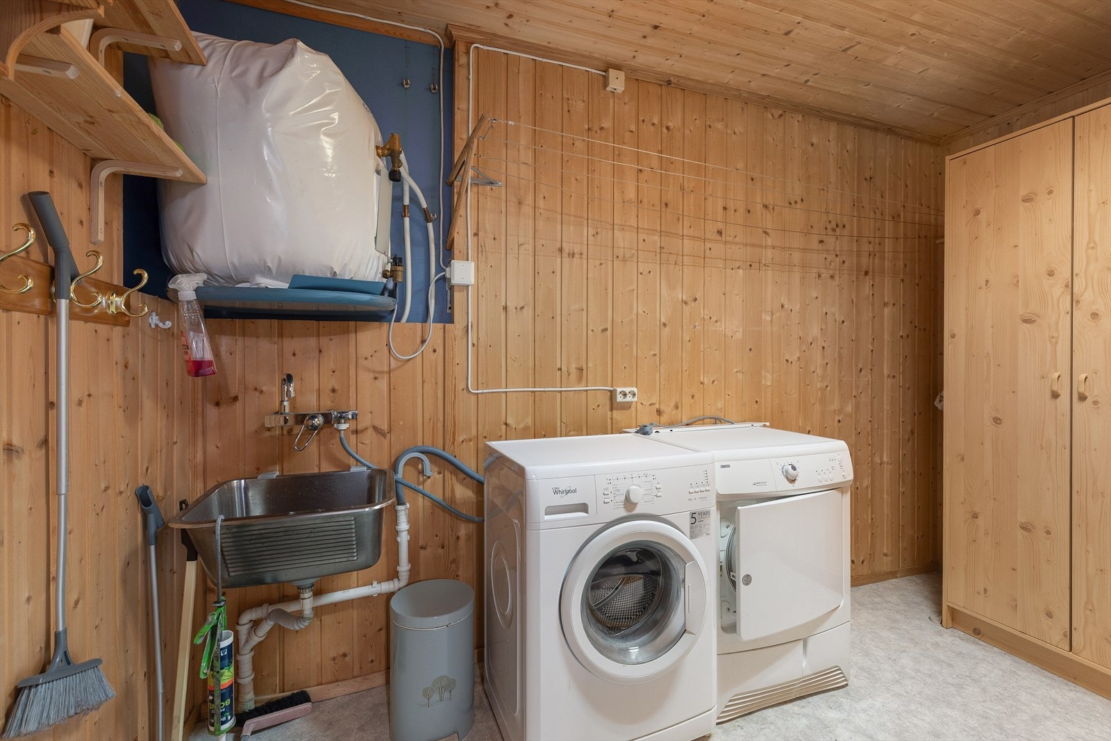 Vaskerom med panel på veggar og golvbelegg på golv. Rommet er utstyrt med utslagsvask, varmtvannsbereder og opplegg for vaskemaskin. Rommet er også utbygd, og gir gode oppbevaringsmoglegheiter. Galleribilde