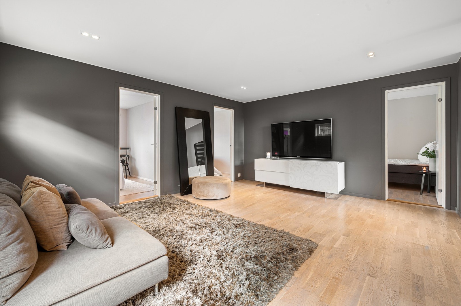 Tv-stuen er malt i lune farger med spotlys i taket. Galleribilde