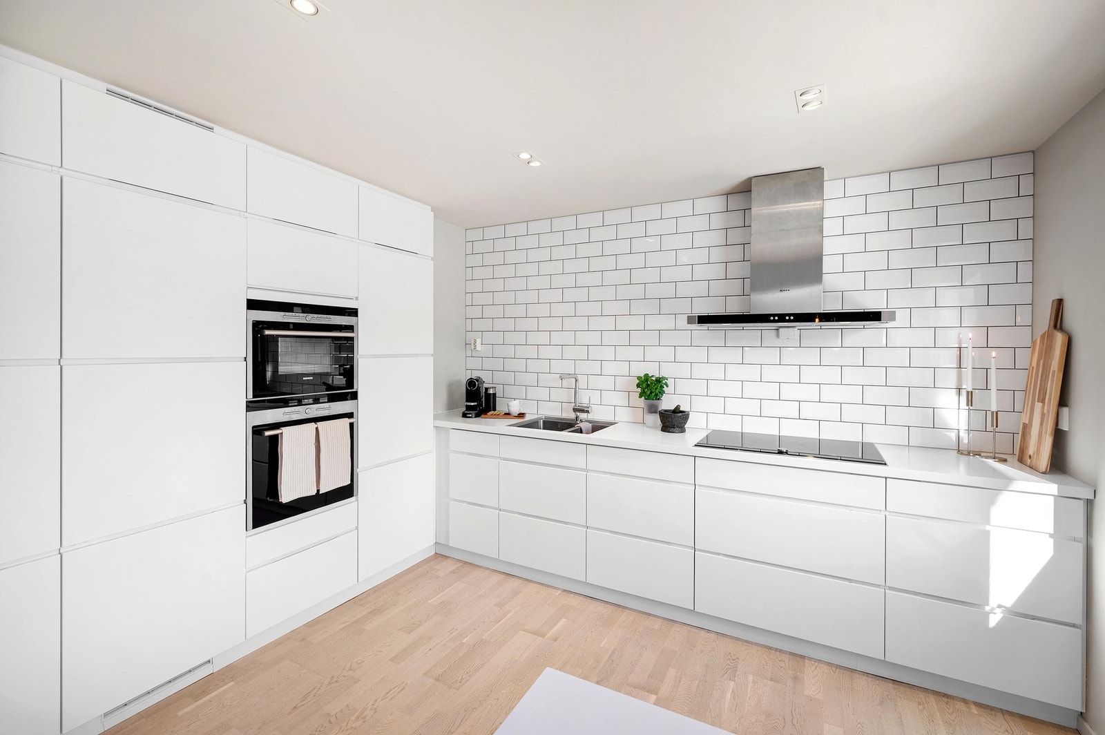 Kjøkkeninnredning med blant annet over- og underskap, høyskap, laminerte benkeplater og komfyrvakt. Galleribilde