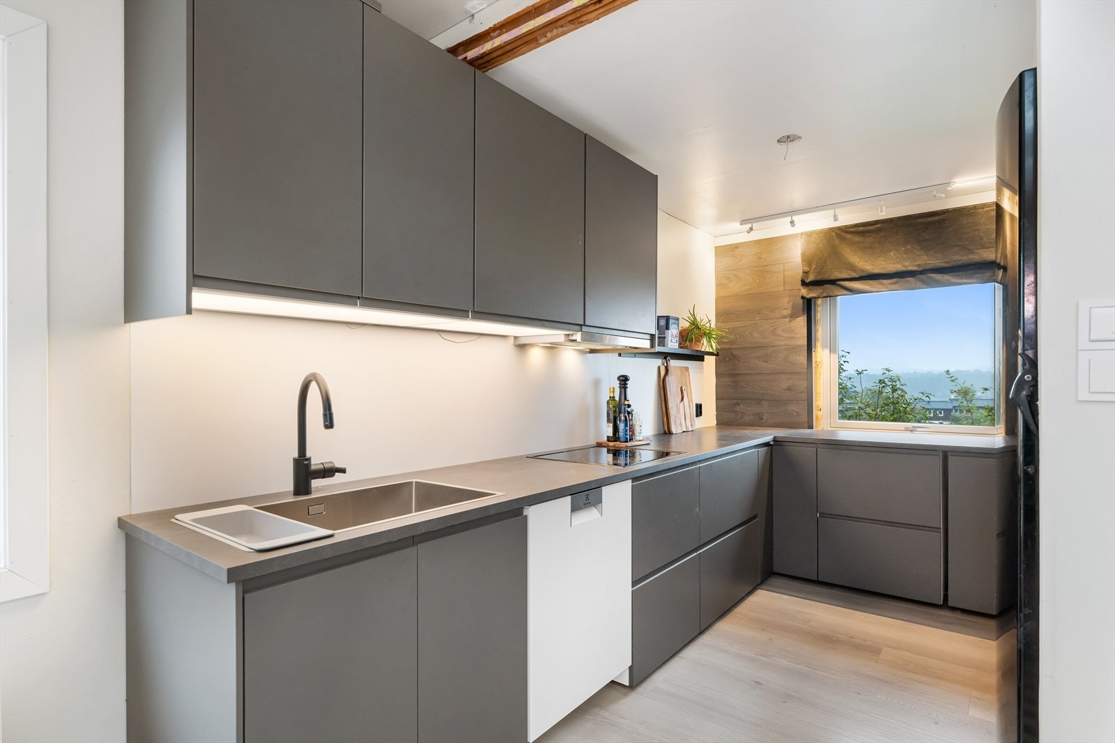 Kjøkken med glatte fronter og laminat benkeplate med nedfelt vask og platetopp. Ventilator plassert over platetopp. Innredningen innehar komfyr, oppvaskmaskin og kjøleskap/frys. Galleribilde