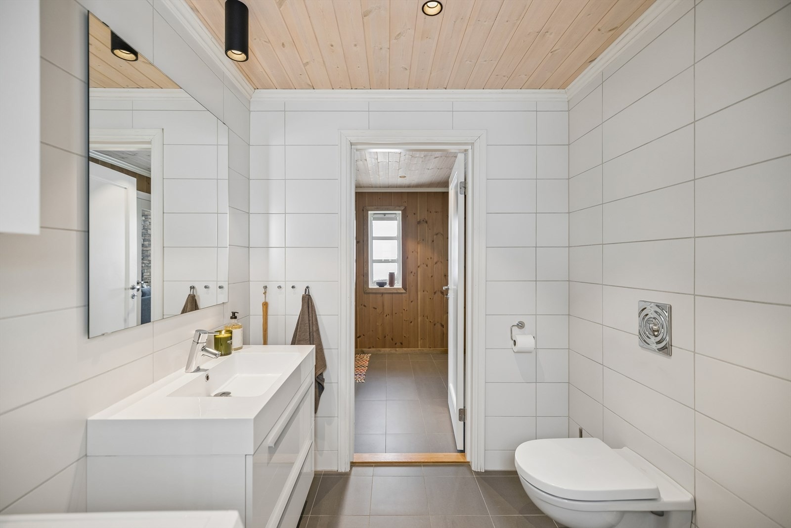 Badet er innredet med en moderne servantseksjon, vegghengt toalett og dusjhjørne med innfellbare dører. Galleribilde