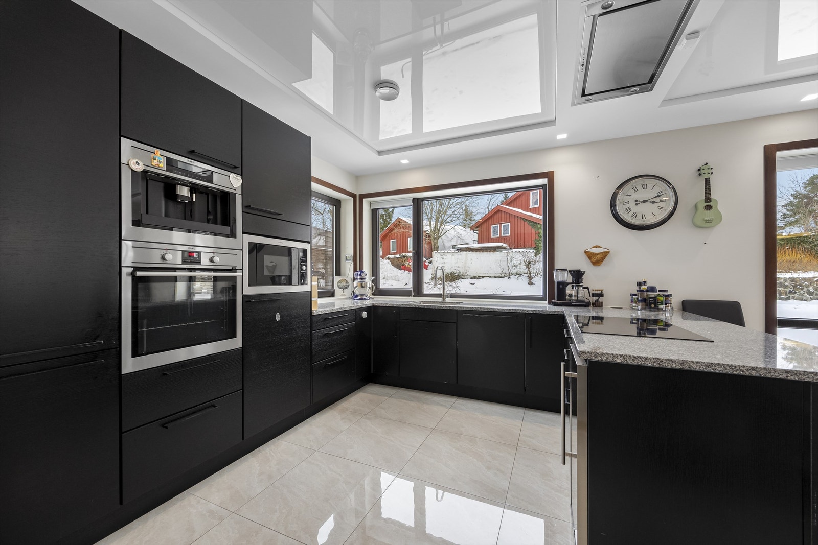 Moderne, sort innredning med integrert stekeovn, mikrobølgeovn og kaffemaskin i praktisk arbeidshøyde. Galleribilde