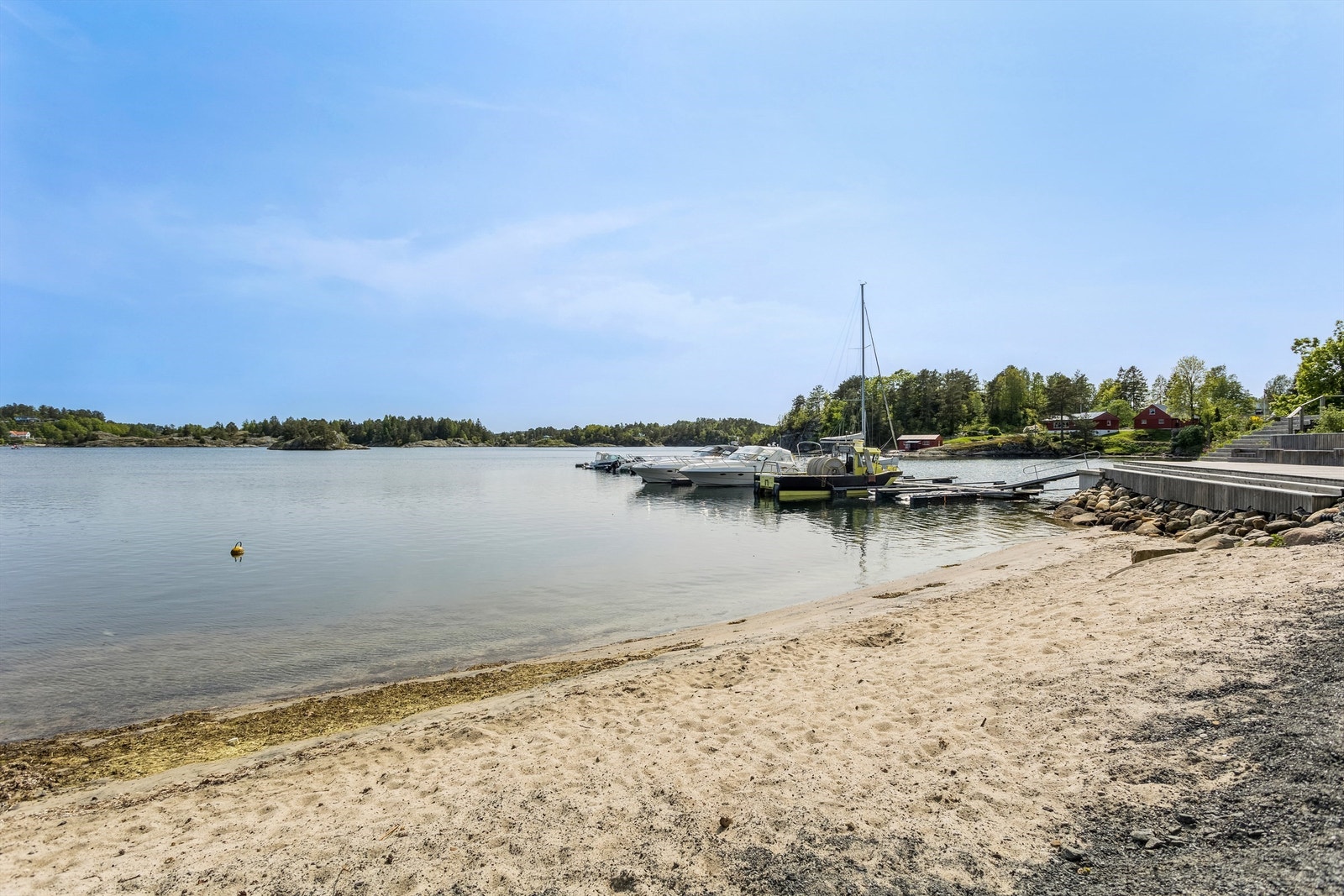 En liten sandstrand ligger i umiddelbar nærhet til bryggeanlegget. Galleribilde
