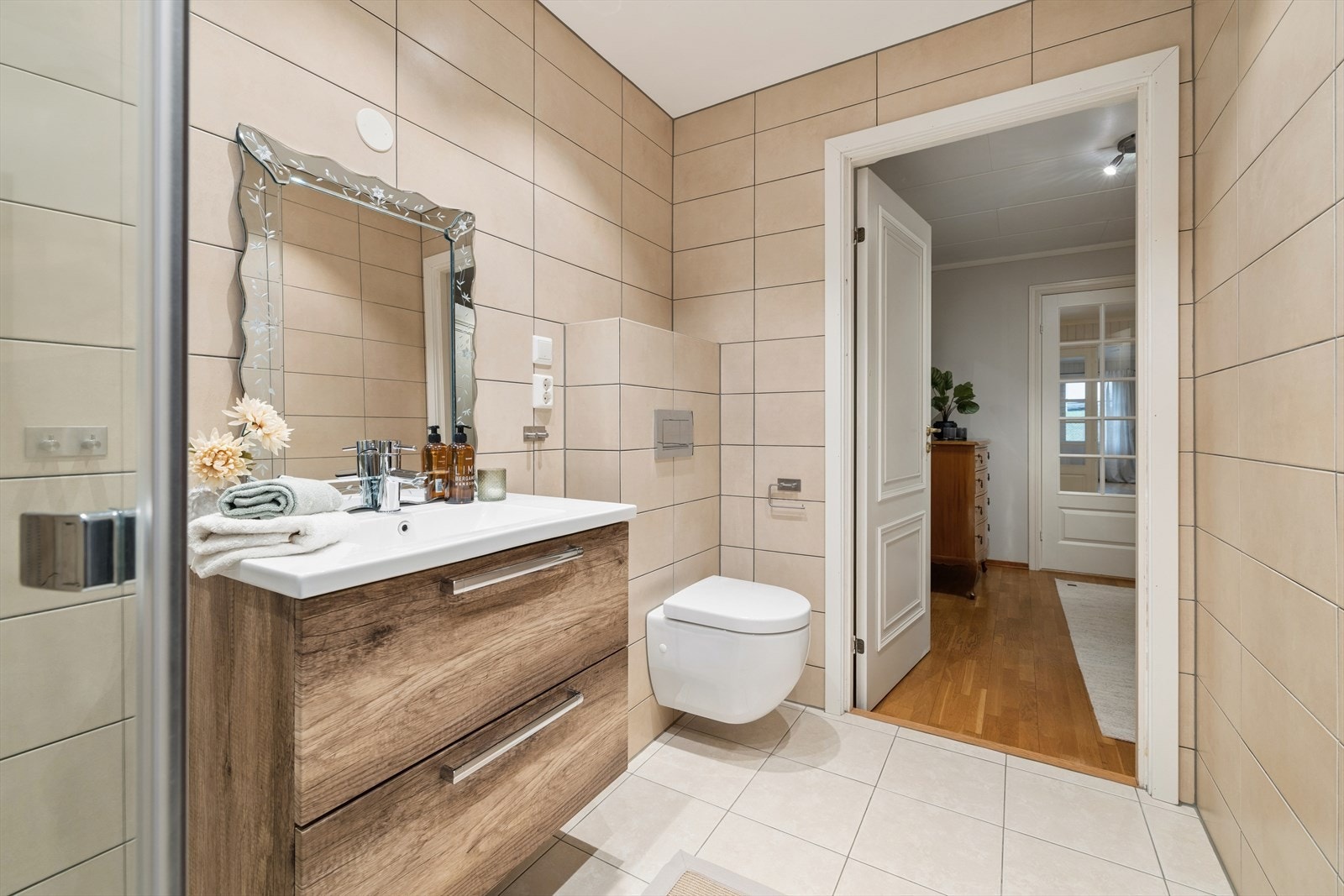 Badet er utstyrt med veggmontert toalett, servantinnredning og dusj med innfellbare vegger. Galleribilde