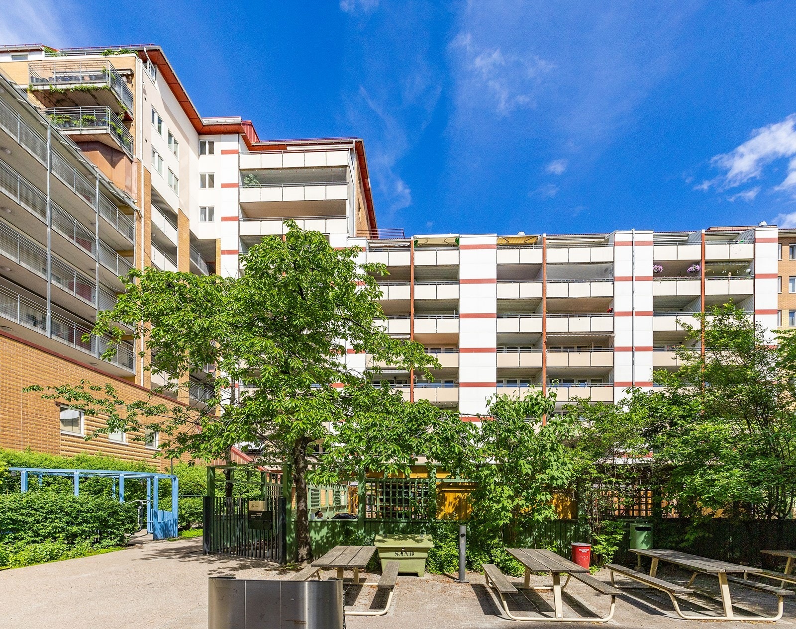 Hyggelig parklignende bakgård med ulike sitteplasser, beplantning og sykkelparkering. Galleribilde