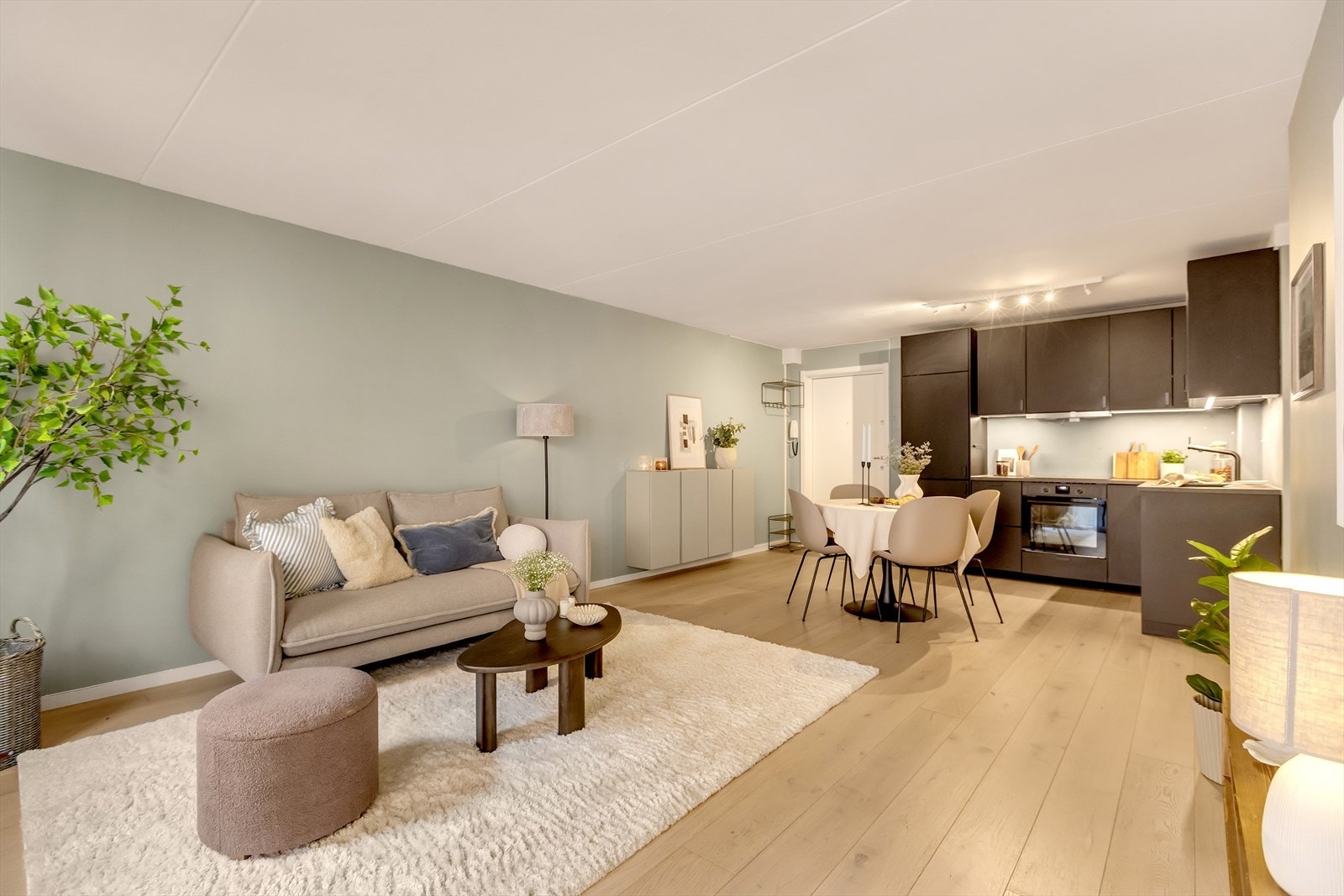 Leiligheten har en romslig og innbydende stue med åpen kjøkkenløsning, som gir en sosial og luftig atmosfære Galleribilde