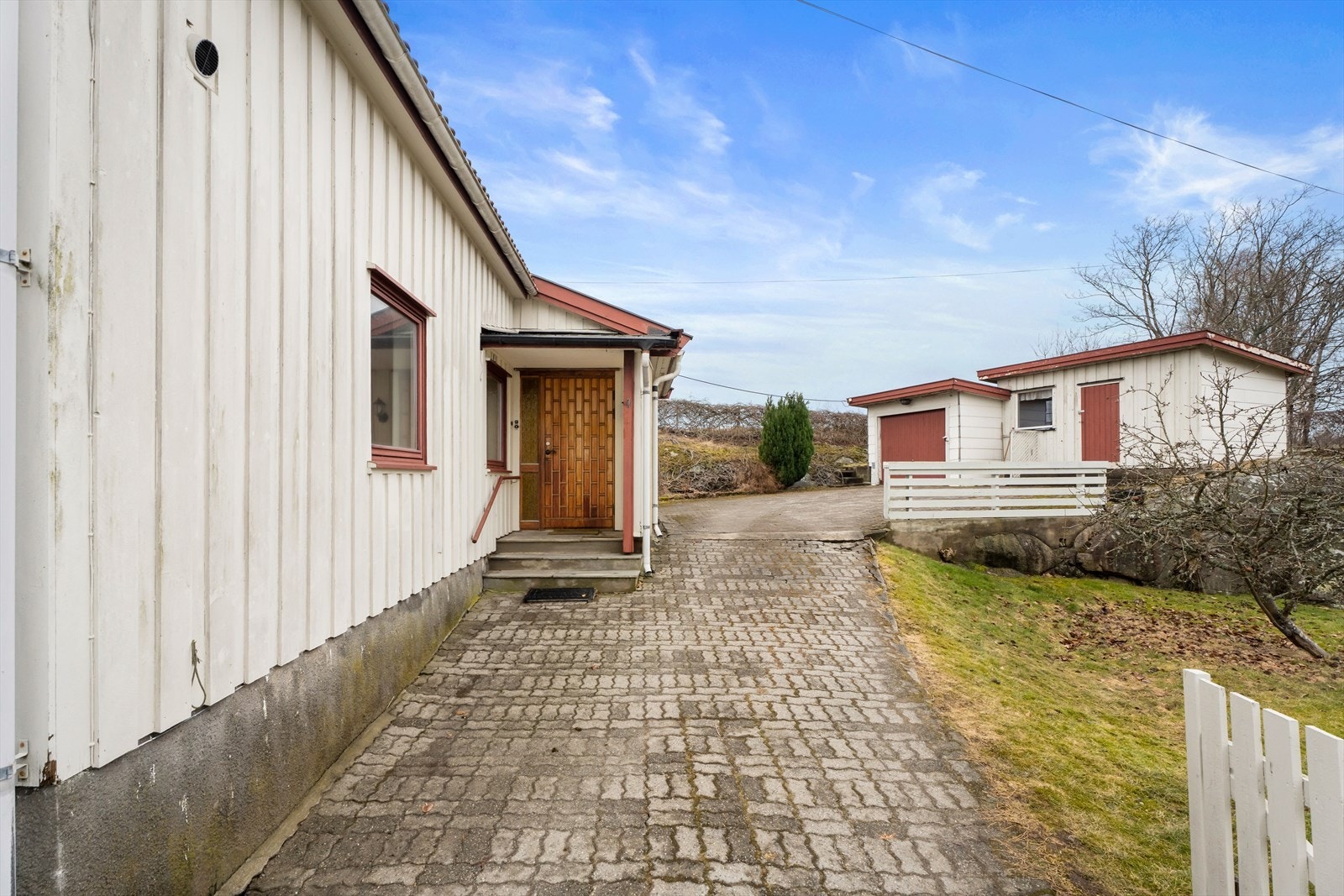 Her blir du introdusert til en stor gårdsplass med belegningsstein og diverse beplantninger som trær og busker. Galleribilde