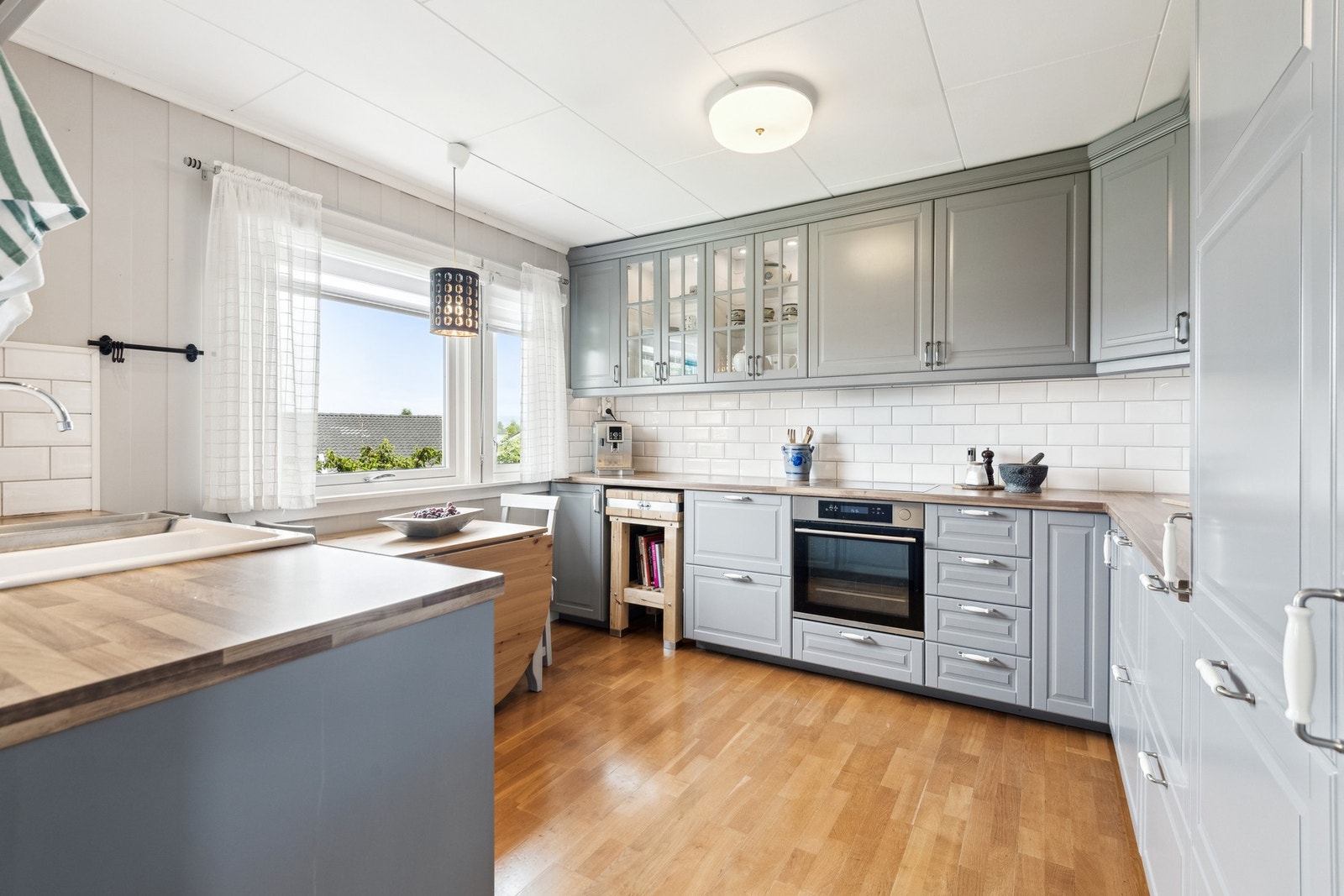 Stort kjøkken med integrerte hvitevarer. Store vindusflater gir godt med lys til en hyggelig frokoststund ved kjøkkenbordet. Galleribilde