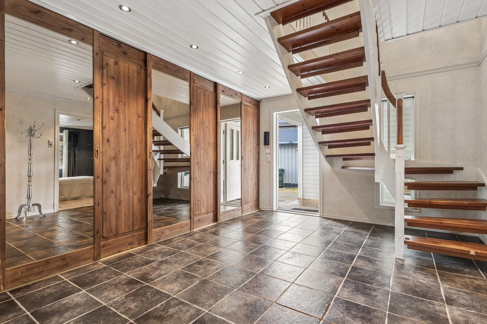 Entréen har rikelig med plass til oppbevaring av yttertøy og sko i en stor skyvedørsgarderobe med speilfronter. Galleribilde