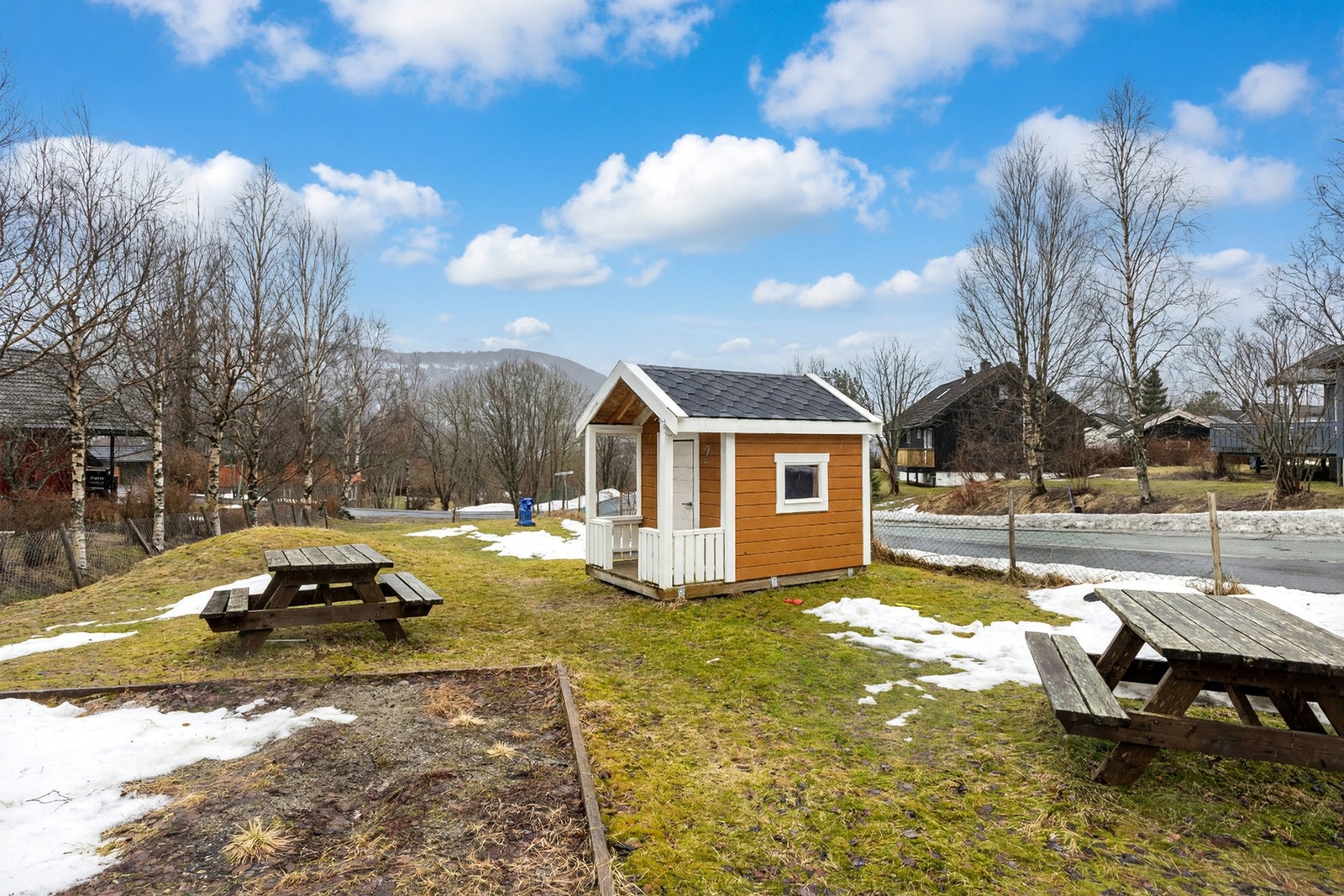 Denne lekeplassen ligger like over gata fra huset, og er til felles bruk for beboerne i feltet. Bildet er AI-redigert fra grå til blå himmel. Galleribilde