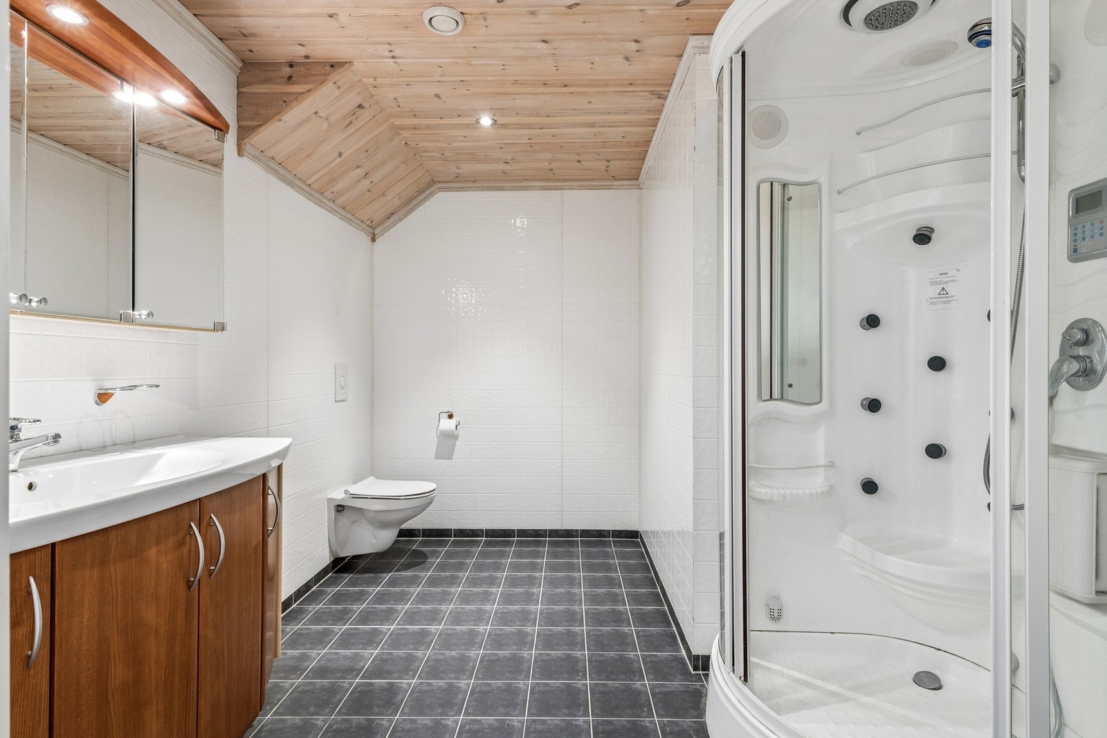 Badet på loftet har alle nødvendige fasiliteter for et funksjonelt rom, flislagt gulv og vannbåren varme, vegghengt toalett og dusjkabinett. Galleribilde