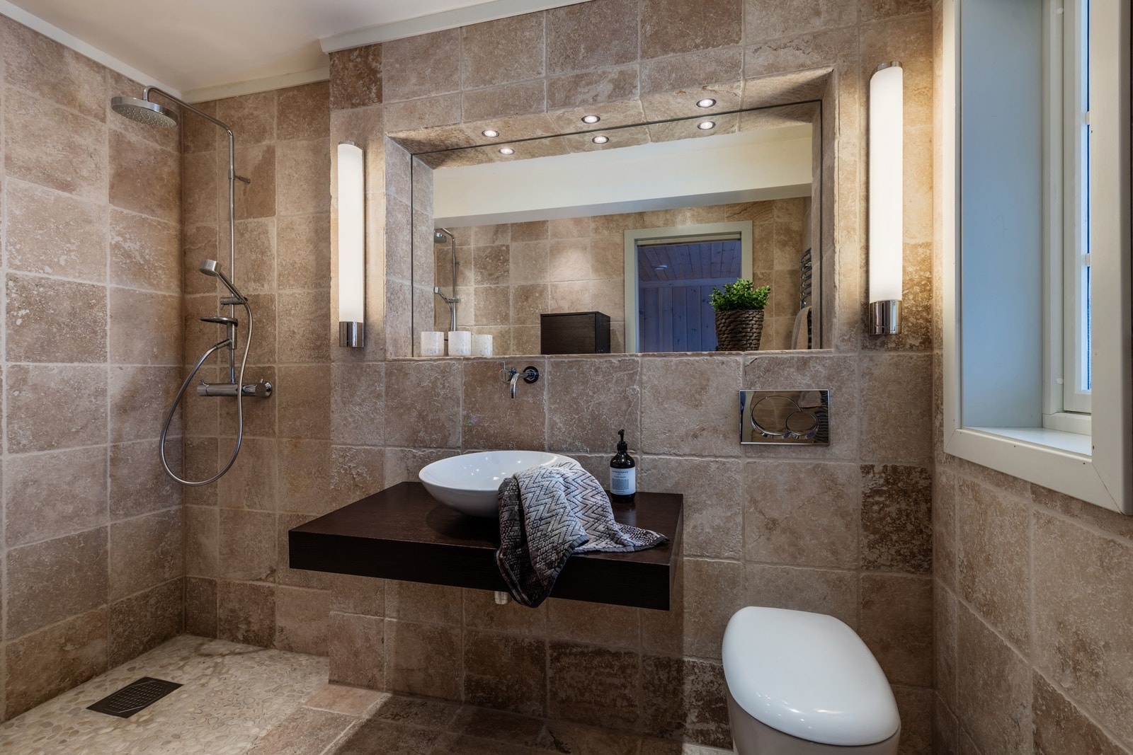 Bad med tilgang fra hovedsoverom har fliser og elvestein på gulv og fliser på vegg. Galleribilde