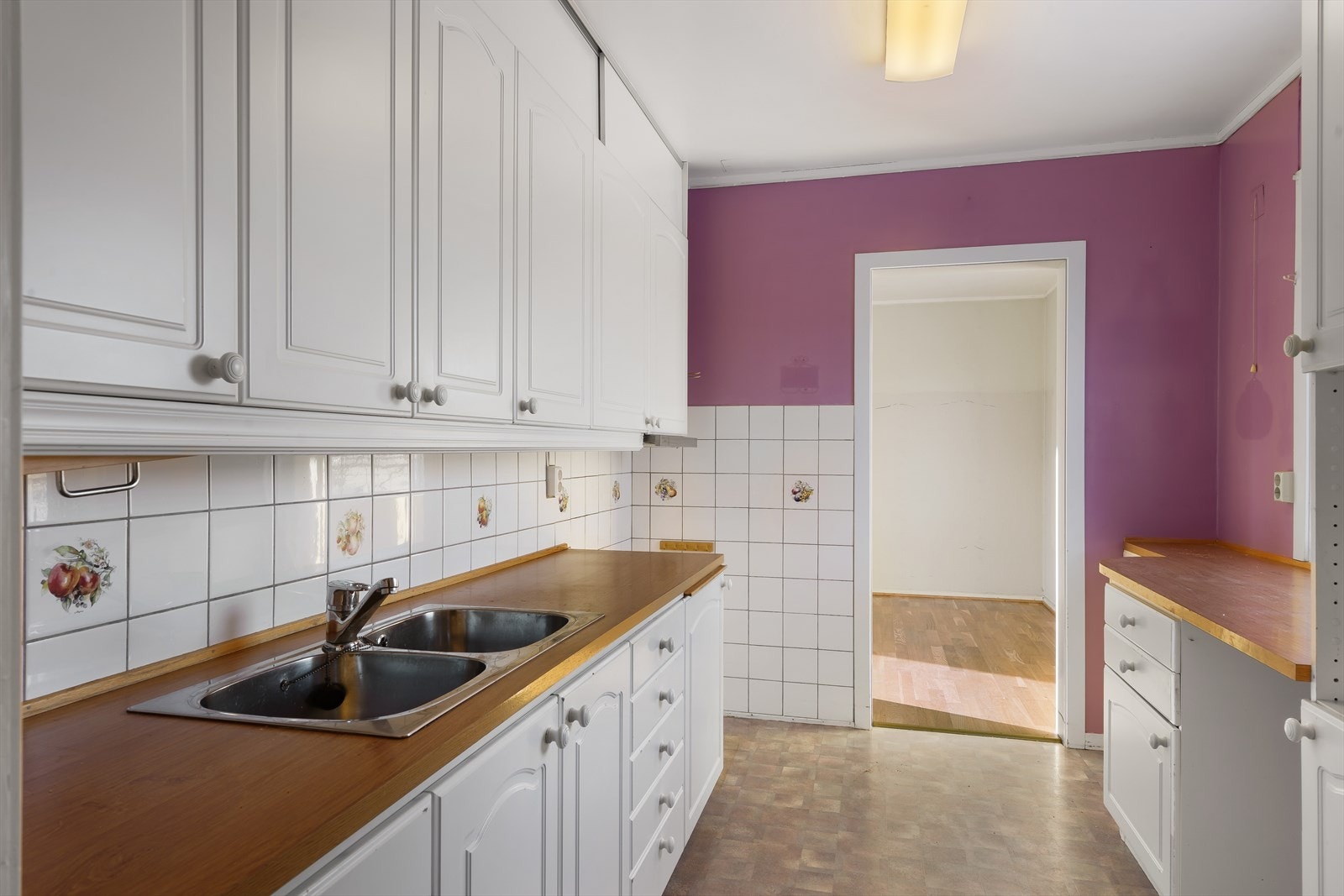 Det er en kombinasjon av under-, over- og høyskap. Fliser på vegg mellom overskap og benkeplate. Galleribilde