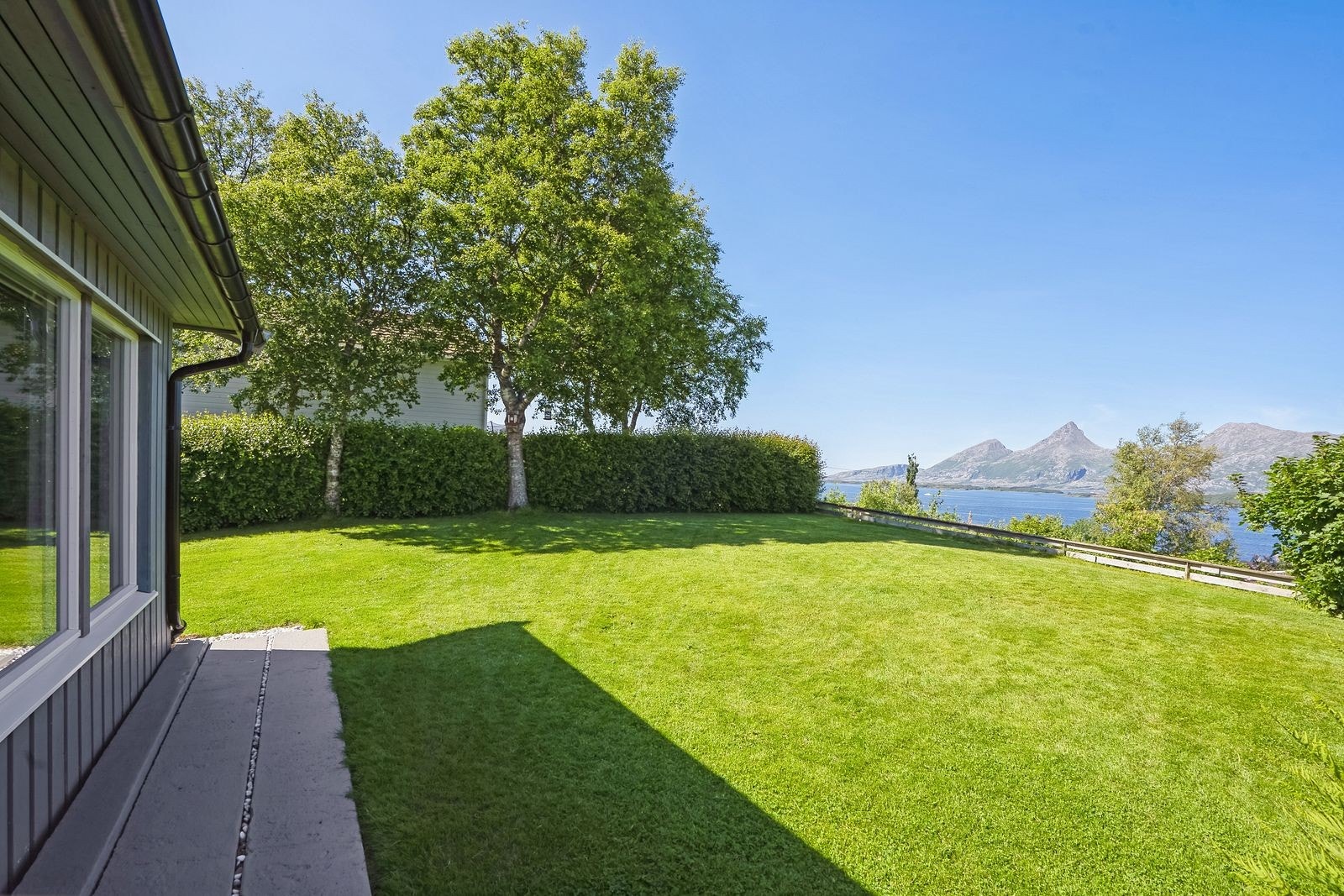 Den grønne plenen strekker seg mot utsikten over fjorden, og gir et fredelig sted for avslaping. Galleribilde