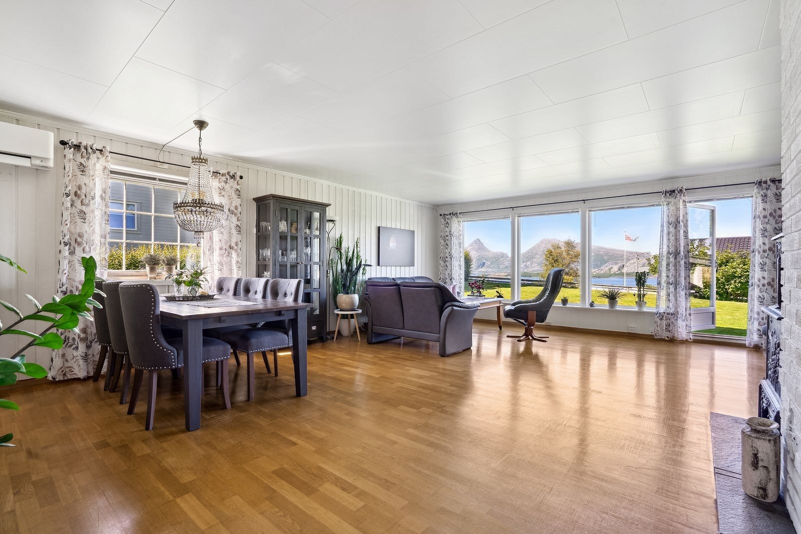 Store vindusflater er vendt mot utsikten. Nydelig med den grønne og flate gressplenen i forkant av utsikten mot sjøen og fjellene. Galleribilde