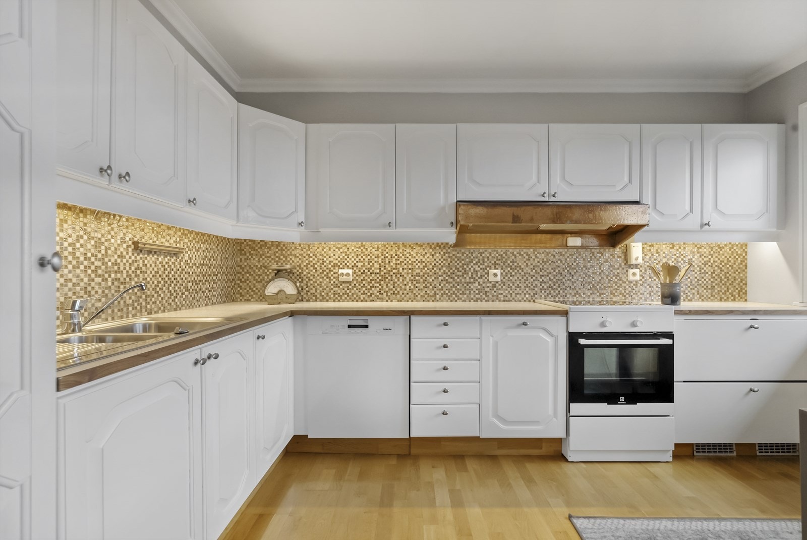 Kjøleskap er integrert i kjøkkenbenk til høgre for komfyr Galleribilde