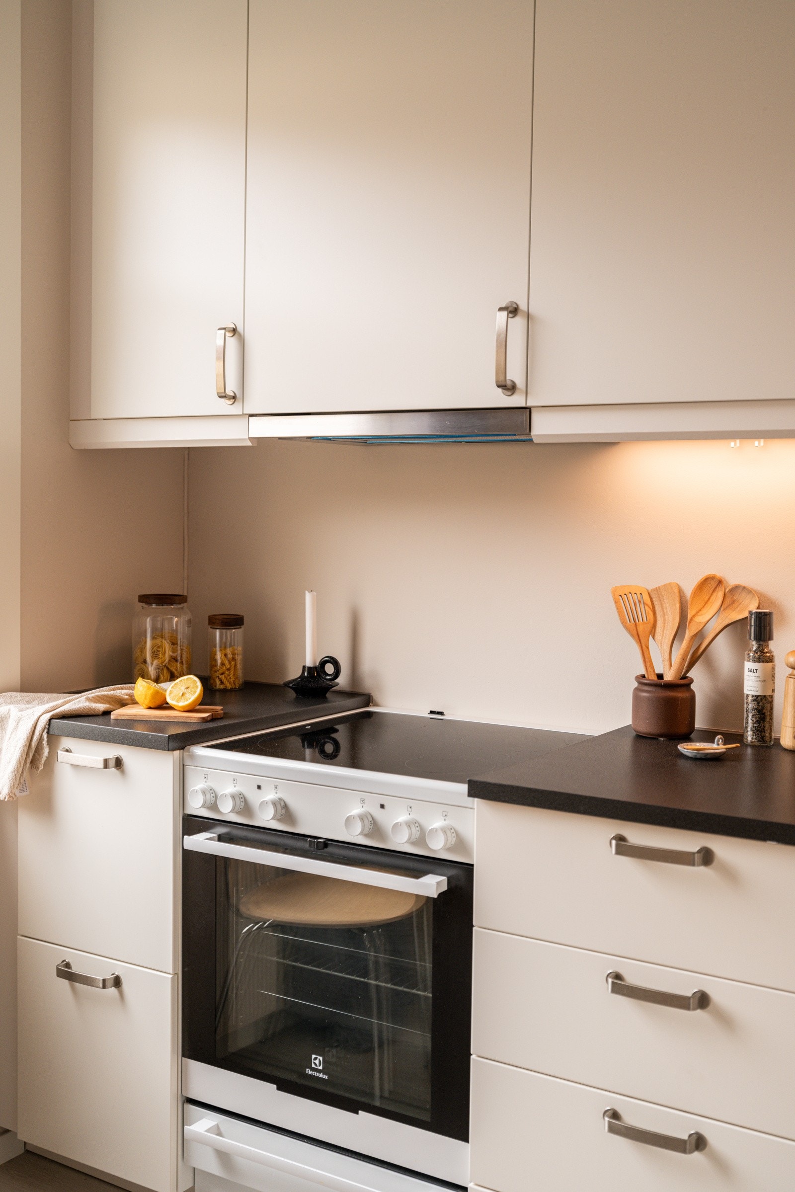 Innredningen har hvite glatte fronter og laminert benkeplate med nedfelt oppvaskkum. Praktisk med belysning under overskapene. Galleribilde