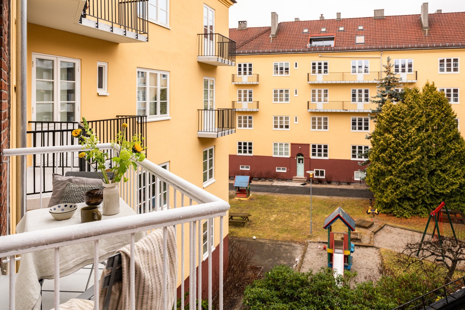 Balkongen har støpt dekke på gulv og plass til et koselig kafé-sett. Galleribilde