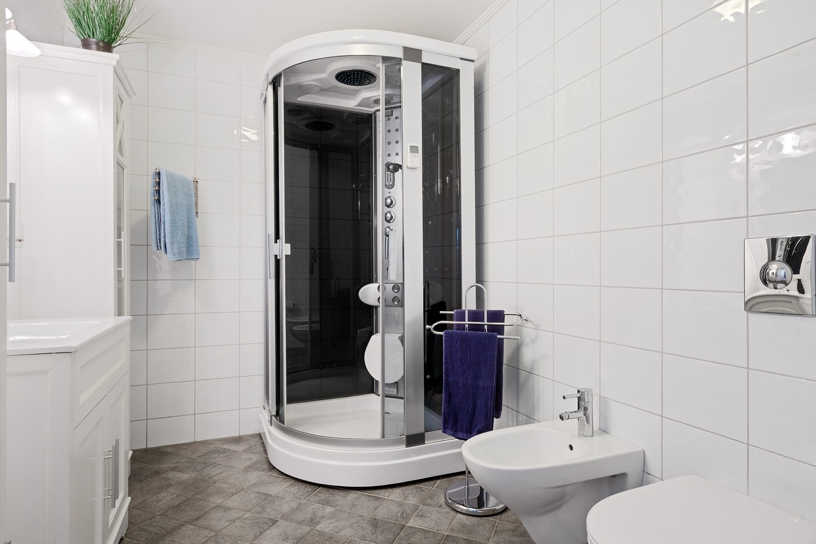 Badet er utstyrt med toalett, bidé, servantinnredning og dusjkabinett. Galleribilde
