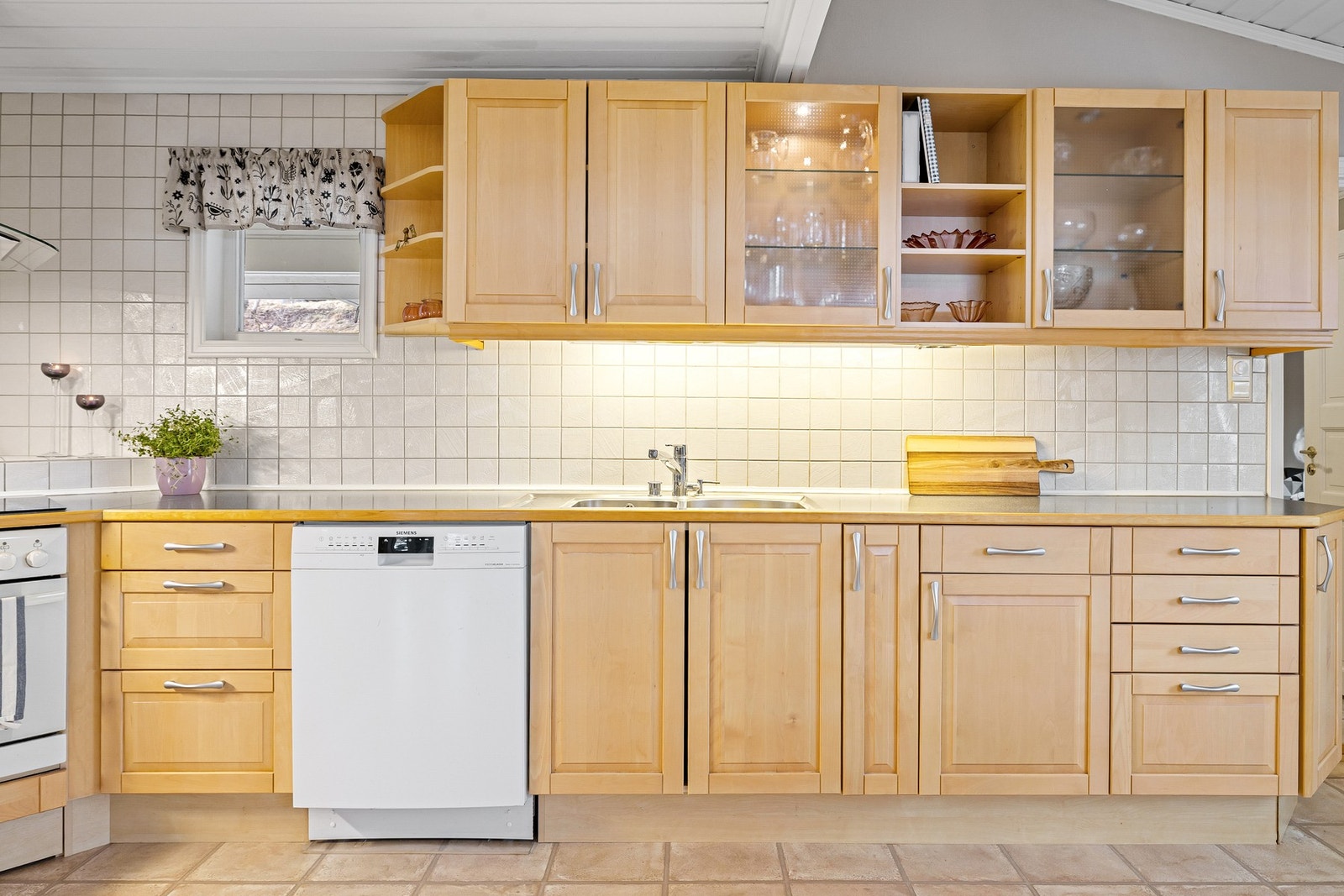 Praktisk kjøkken med mye benke - og skapplass. Det er flis mellom benkeplate og overskap. Galleribilde