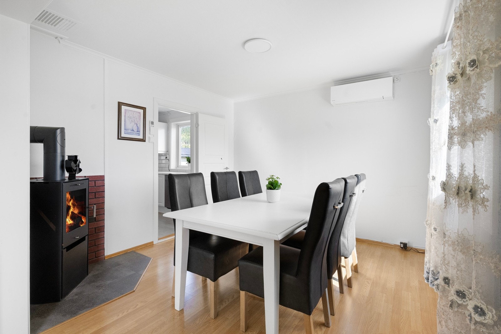 Stuen har en koselig vedovn som skaper varme og stemning på kjølige dager, i tillegg til en moderne varmepumpe (installert 2025) for effektiv oppvarming og kjøling Galleribilde