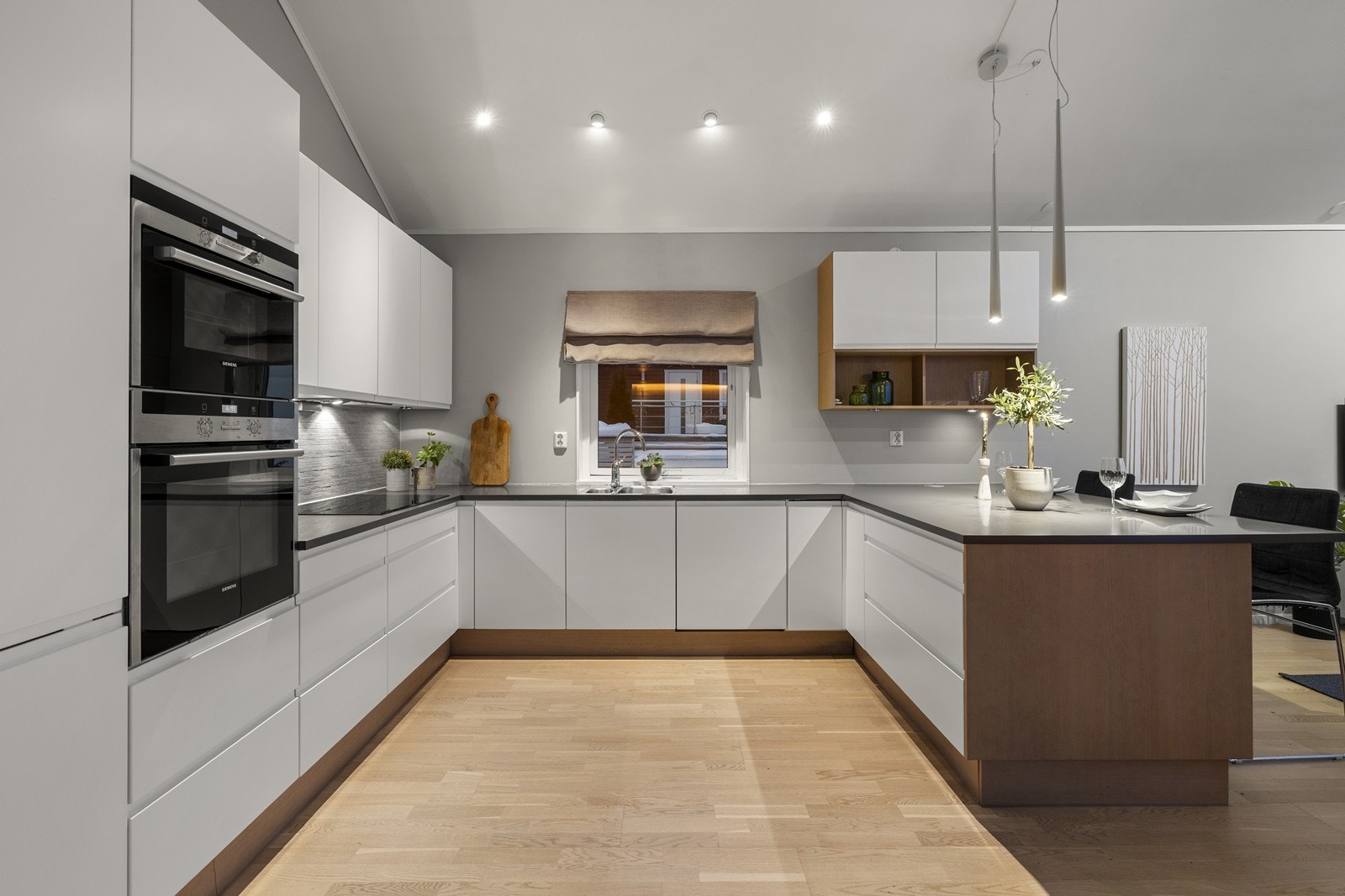 Moderne kjøkken i åpen løsning med stuen, smart adskilt med en praktisk barløsning som skaper en naturlig soneinndeling. Galleribilde