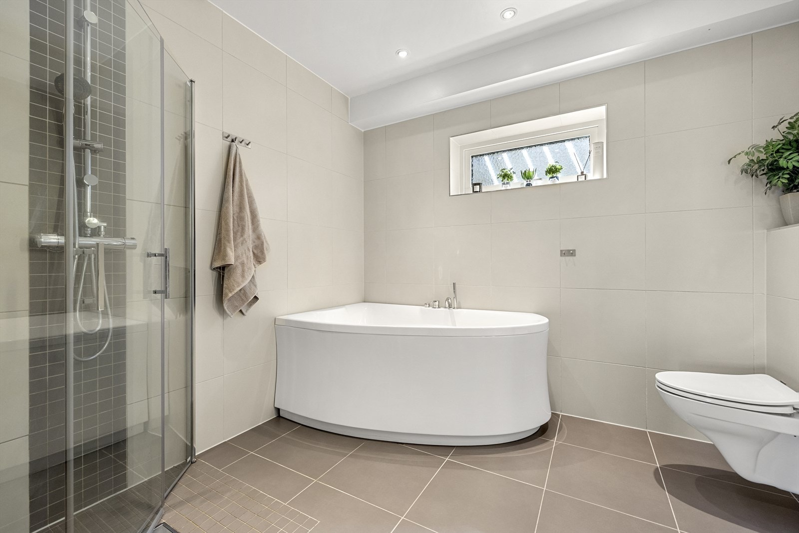 Dusjnisje med innfellbare glassdører, speil med belysning, downlights i taket og varmekabler i gulvet gir badet god komfort. Galleribilde