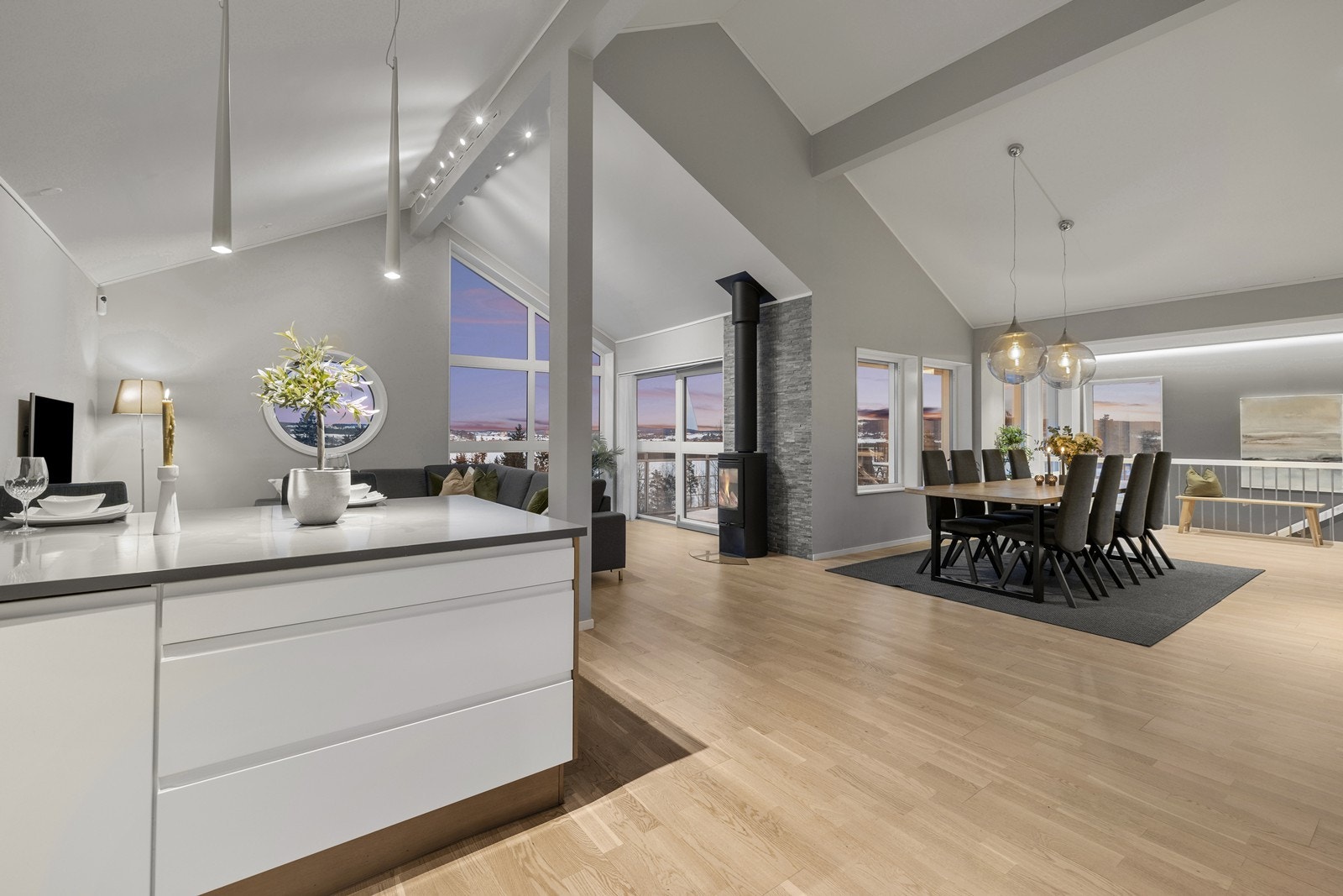 Lys og innbydende stue i åpen løsning med kjøkken og spisestue, med generøs takhøyde og store vindusflater som gir en luftig romfølelse. Galleribilde