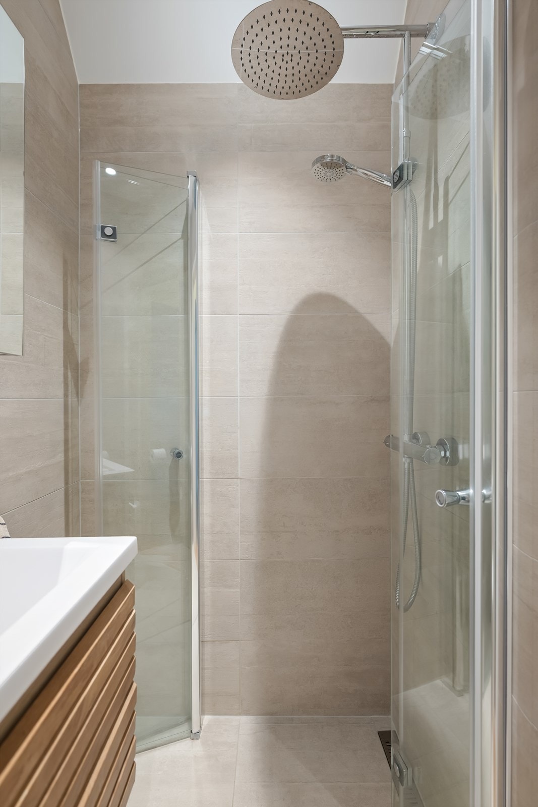 Dusjhjørnet har praktiske, innfellbare glassdører som frigjør gulvplass når dusjen ikke er i bruk. Galleribilde