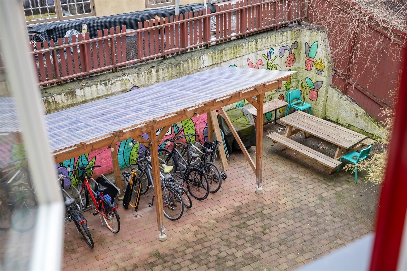 Leiligheten vender ut mot borettslagets bakgård med sittegrupper og overbygget sykkelparkering. Galleribilde