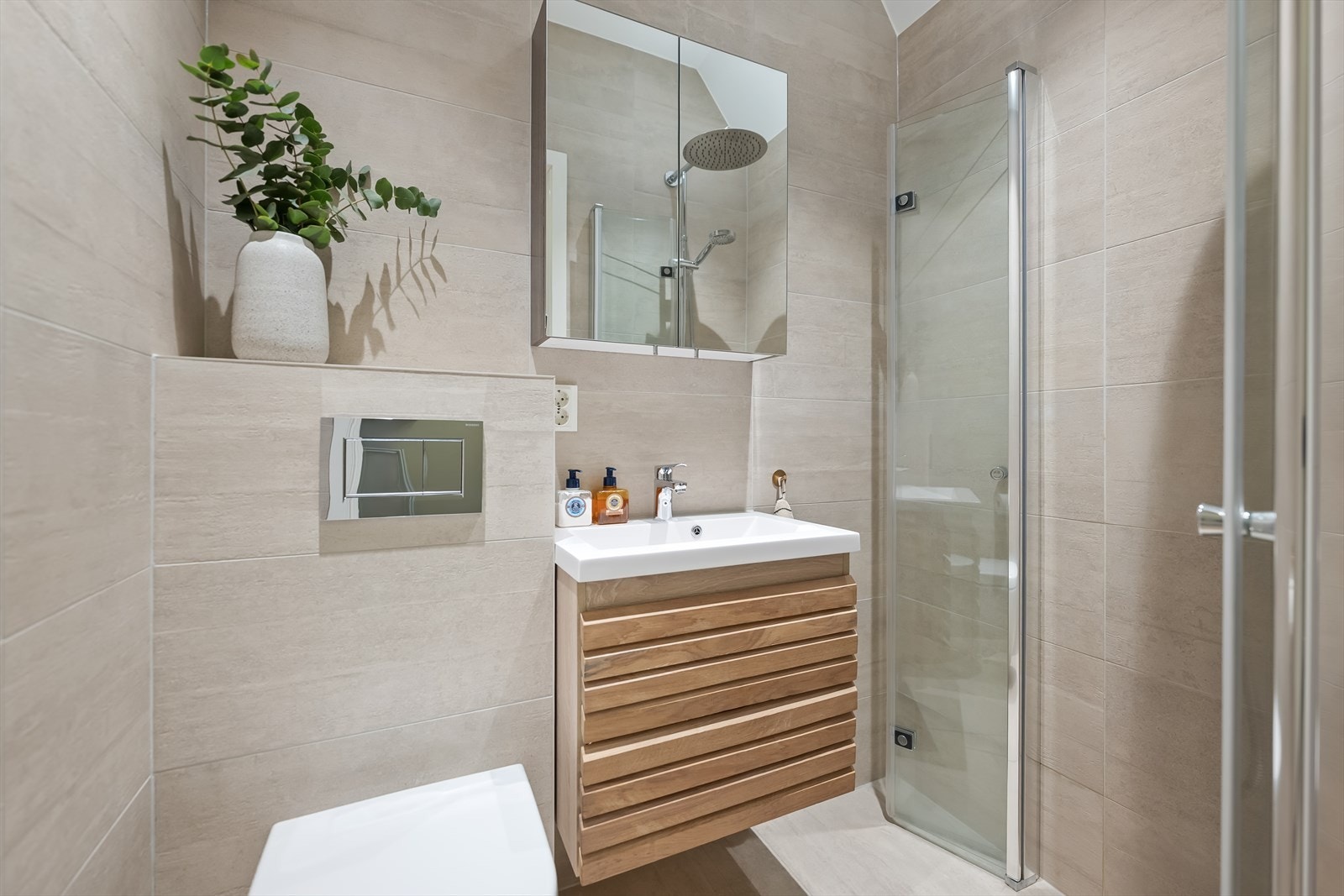 Innredningen består av servant med underskap, speilskap med belysning og vegghengt toalett. Det er varmekabler i gulvet og integrert belysning i himlingen. Galleribilde