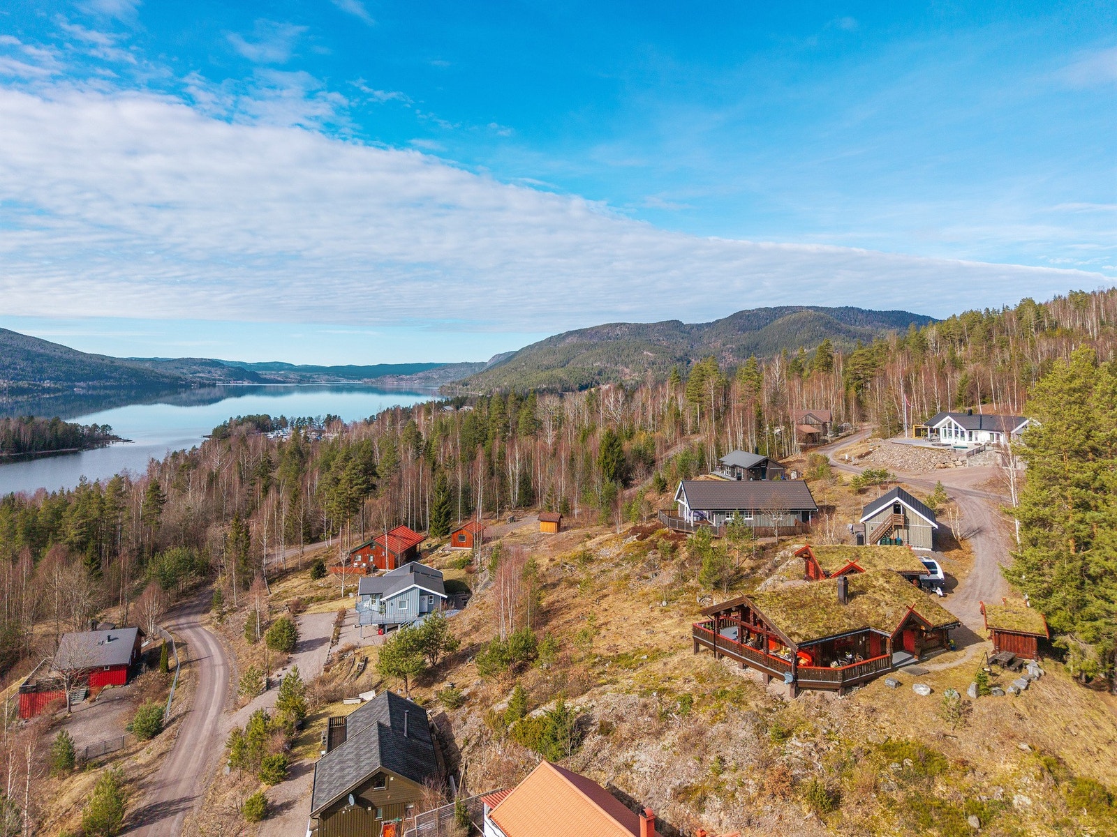 Oversiktsbilde av området som viser den naturskjønne beliggenheten med vann, skog og spredt bebyggelse. Galleribilde
