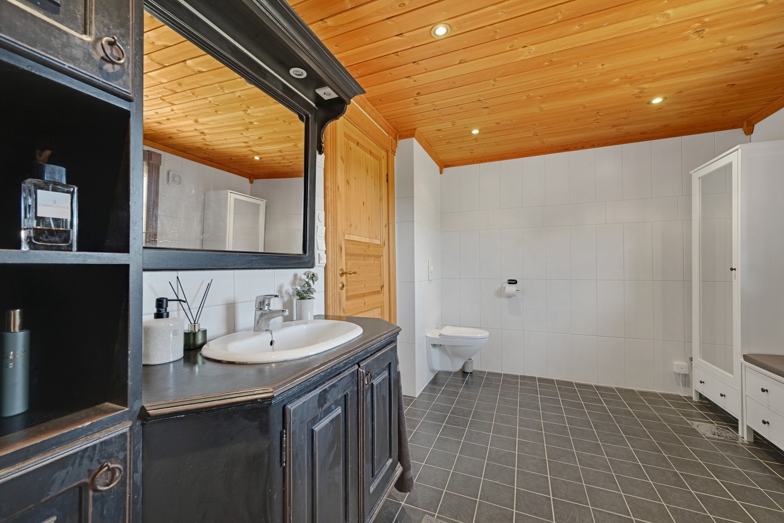 Badet er flislagt og inneholder servant med innredning, veggmontert wc og dusjkabinett. Galleribilde