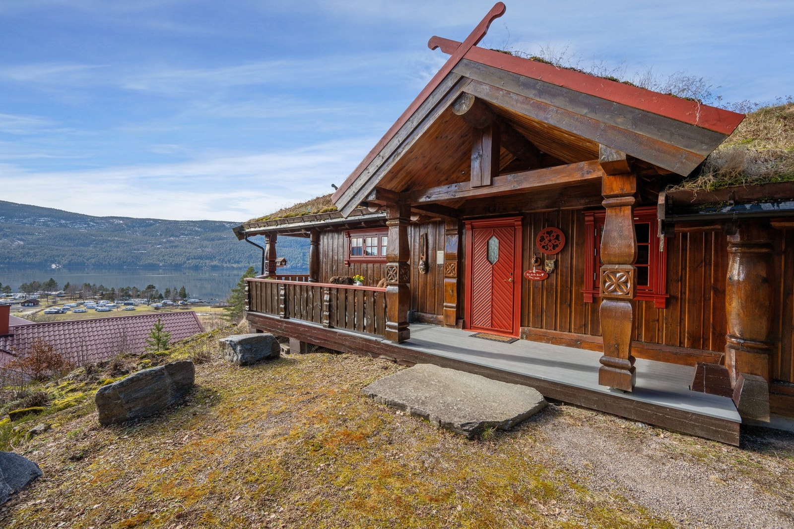 Vi har flyttet oss tilbake til hytta - her ser vi et innbydende inngangsparti med flotte utskjæringer og karakteristisk rød dør som gir hytta et unikt og autentisk preg. Galleribilde