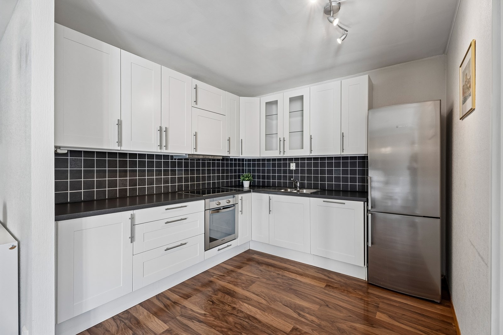 Kjøkkeninnredning fra Ikea med slette fronter, laminatbenkeplate og integrert stekeovn, platetopp og oppvaskmaskin. Galleribilde