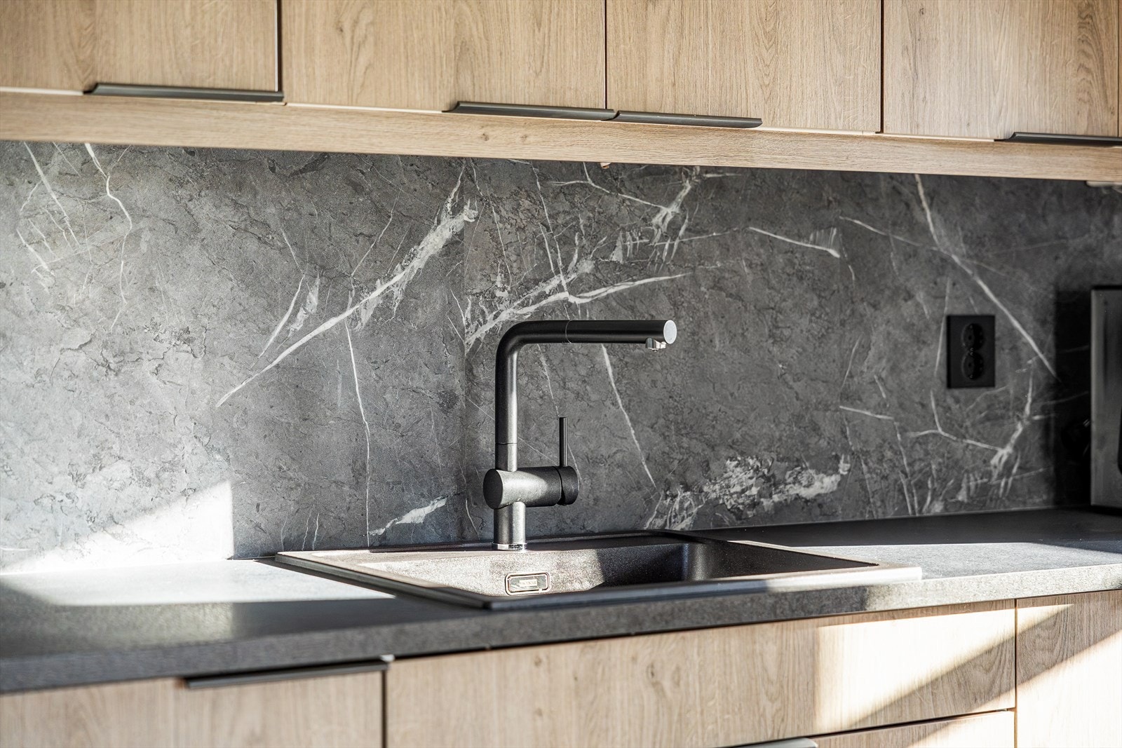 Over benkeplaten finner du en gjennomført og dekorativ vegg som tilfører kjøkkenet det lille ekstra. Det stilrene uttrykket gir rommet karakter og binder sammen det moderne interiøret på en elegant måte. Galleribilde