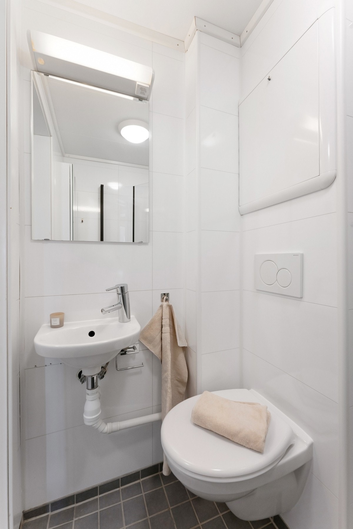 Badet er innredet med vegghengt toalett, servant og speil på veggen. Galleribilde