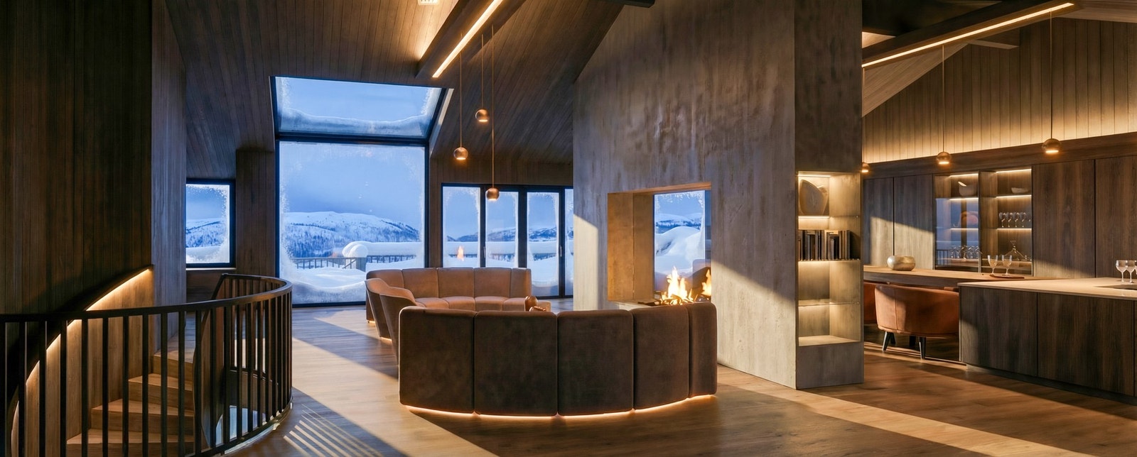 Den åpne peisen danner et naturlig midtpunkt mellom stue og kjøkken, og gir hytta en unik, varm og innbydende karakter Galleribilde