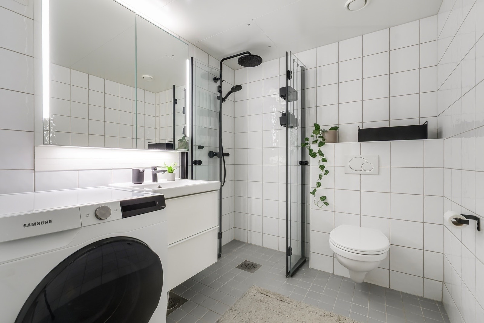 Flislagt bad med varmekabler i gulv. Badet er innredet med veggmontert toalett, servant med skap, speil med belysning og dusjhjørne med vegger i herdet glass. Det er opplegg for vaskemaskin. Badet har balansert ventilasjon med avtrekksventil ved dusjsone Galleribilde
