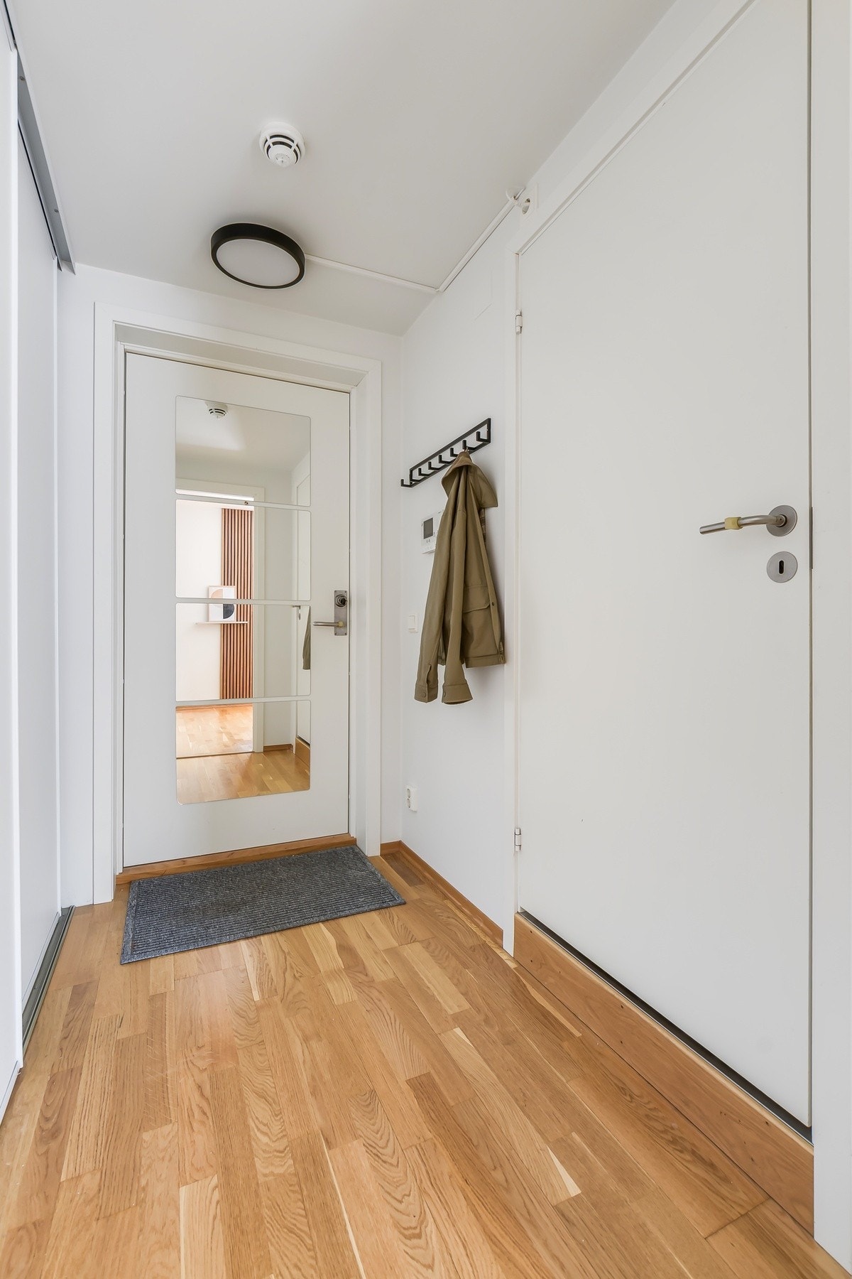 Romslig og innbydende entré med god plass til oppbevaring av yttertøy og sko i praktisk skyvedørsgarderobe. Dørcalling gjør det enkelt å ta imot gjester Galleribilde