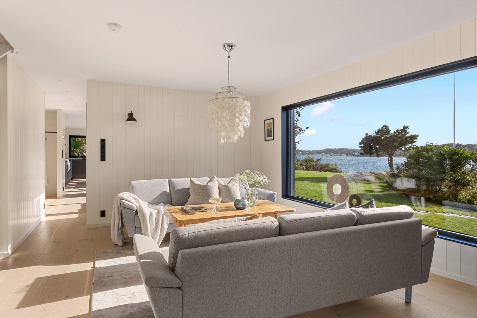 Stuen åpenbarer seg med store vindusflater som slipper inn rikelig med naturlig lys og sjøens panorama Galleribilde