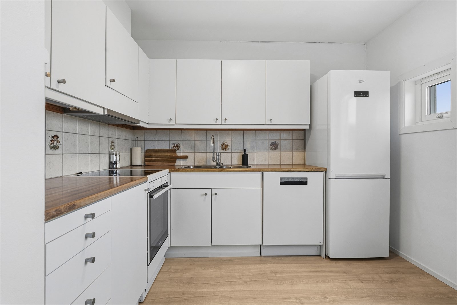 Kjøkkeninnredningen antas å være fra byggeåret og fremstår med tidløse, glatte fronter og en praktisk benkeplate i laminat som tåler daglig bruk godt. Det er installert kjøkkenventilator med avtrekk ut, noe som sikrer effektiv bortledning av matos. Galleribilde