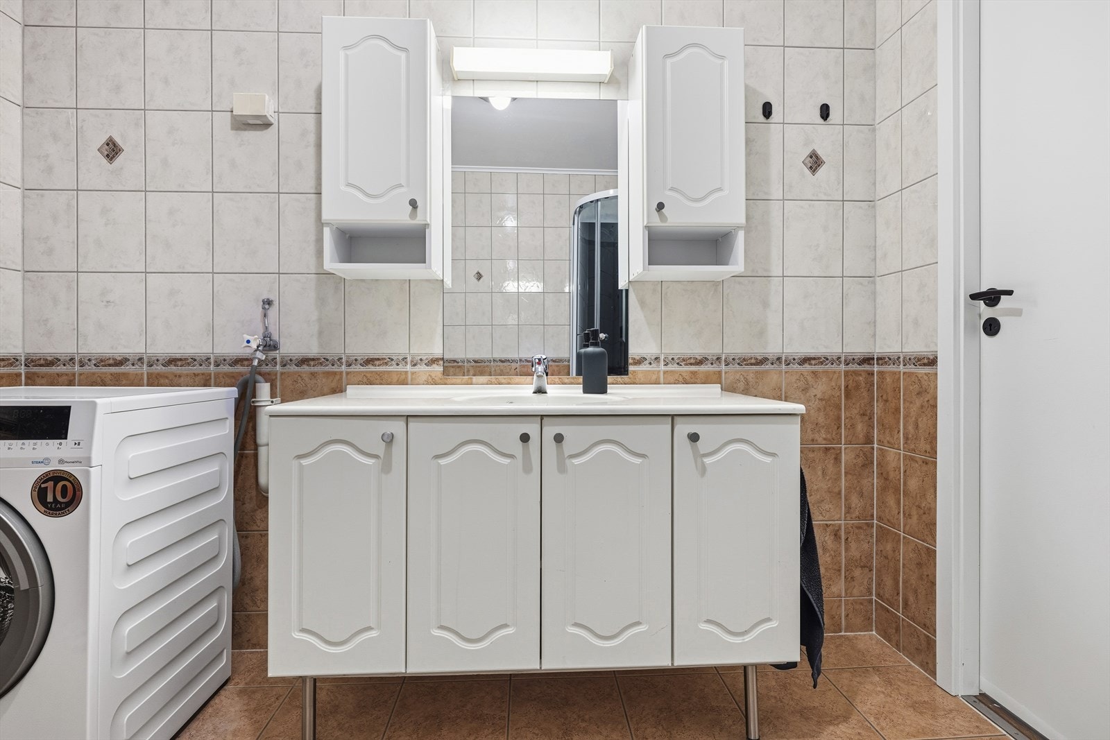 Rommet fremstår som funksjonelt med flislagte gulv og vegger som både er lettstelte og gir et klassisk uttrykk. I taket er det malte flater som bidrar til et lyst og rent inntrykk. Galleribilde