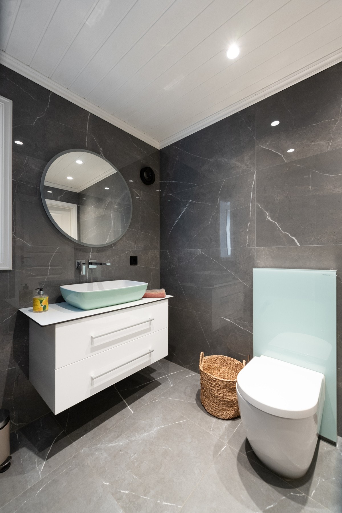 Moderne bad med vegghengt toalett, servant med underskap og speil. Galleribilde