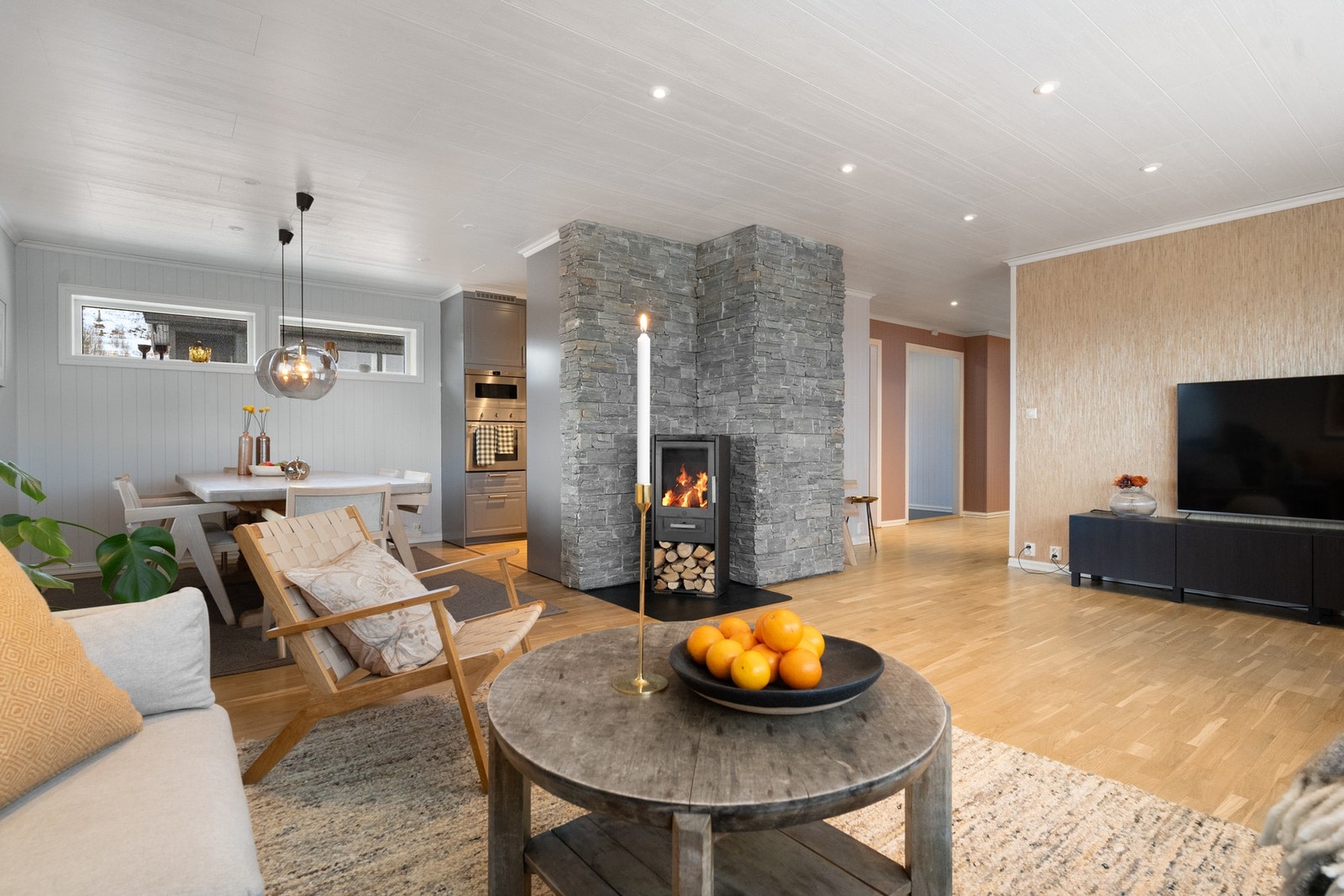 Romslig stue med peis og åpen løsning mot spiseplass. Galleribilde