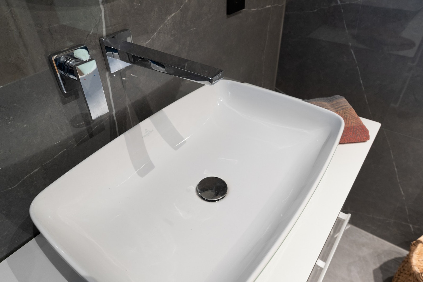 Moderne servant med veggmontert armatur og mørke fliser. Galleribilde